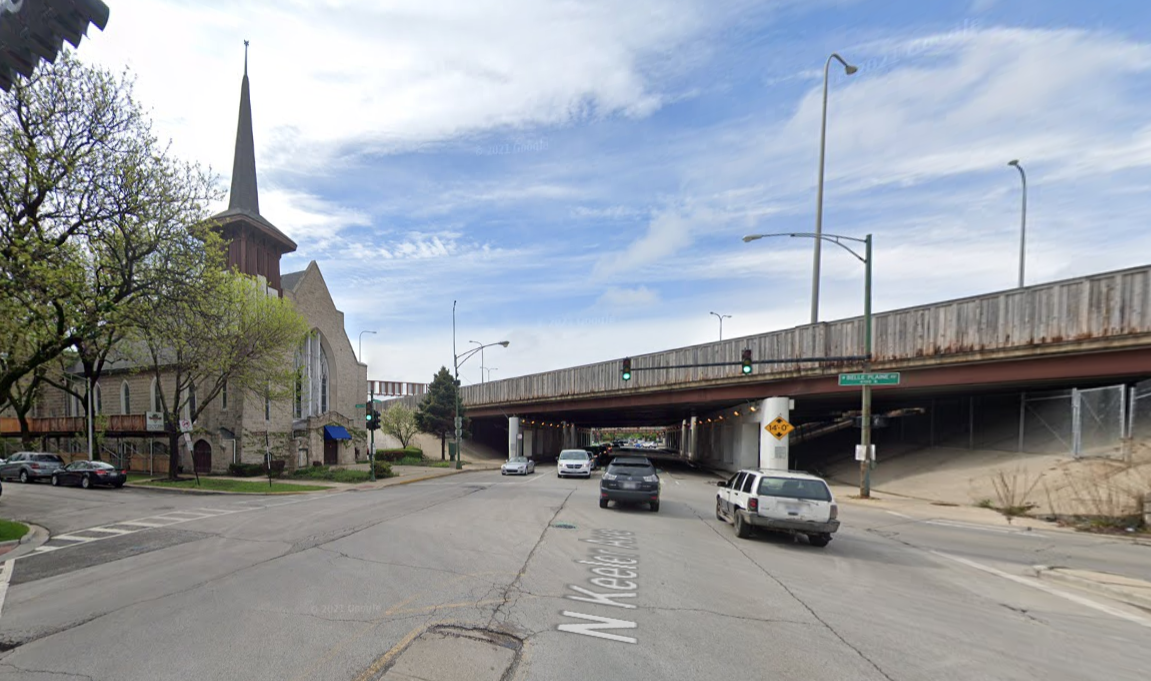 Church on the left, standing on a wide street next to a huge highway viaduct.