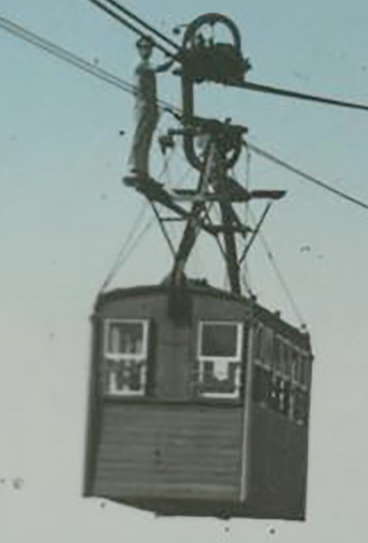 Man standing on top of a hanging cablecar cabin